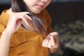 Woman hand holding her long hair with looking at damaged splitting ends of hair care problems