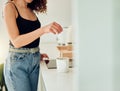 Woman hand holding herbal tea bag over cup of boiling water, making chai in kitchen taking a break. Female barista woman