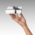 Woman Hand holding Holiday Present White Box with Grey Ribbon