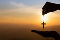 Woman hand holding holy lift of christian cross with light sunset background Royalty Free Stock Photo