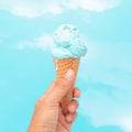 Woman hand holding ice cream blue cone in hot summer day on Cloud sky outdoor background Royalty Free Stock Photo