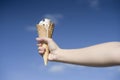 Woman hand holding ice cream cone on a hot summer blue sky background Royalty Free Stock Photo