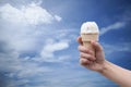 A woman hand holding Ice cream cone with summer blue sky and clouds in background,colorful picture style Royalty Free Stock Photo