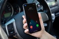 Woman hand holding iPhone with Widgets call IOS14 the car