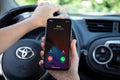 Woman hand holding iPhone with Widgets call IOS14 the car