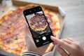 Woman hand holding iPhone X with photo pizza delivery Royalty Free Stock Photo