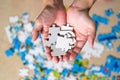 Woman hand holding jigsaw puzzle. Home puzzle game. Autism awareness. Mental health care concept with jigsaw pattern supported by