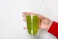 Woman hand holding kiwi smothie glass against white wall. Space for text Royalty Free Stock Photo