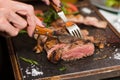Woman hand holding knife and fork cutting grilled beef steak Royalty Free Stock Photo