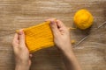 Woman hand holding knitting pattern wrong side by yellow yarn on wooden background