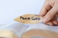 Woman hand holding leaf with a written message to praise God our Father and our Lord Jesus Christ