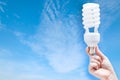 Woman hand holding light bulb on blue sky background Royalty Free Stock Photo