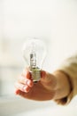 Woman hand holding light bulb on cream background with copy space. Creative idea, new business plan, motivation Royalty Free Stock Photo