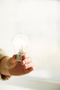 Woman hand holding light bulb on cream background with copy space. Creative idea, new business plan, motivation Royalty Free Stock Photo