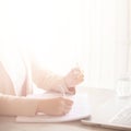 Woman hand holding light bulb, notebook, laptop, pen, documents on cream background with copy space. Creative idea, new Royalty Free Stock Photo