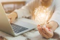 Woman hand holding light bulb and using laptop on wooden desk. Concept new idea with innovation and creativity Royalty Free Stock Photo