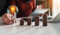 Woman hand holding lightbulb with coins stack on desk. Royalty Free Stock Photo