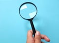 Woman Hand holding Magnifying glass  on a blue backgrou Royalty Free Stock Photo