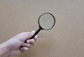 Woman hand holding  Magnifying glass  isolate on a brown background Royalty Free Stock Photo