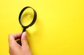 Woman hand holding Magnifying glass  on a yellow background Royalty Free Stock Photo