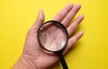 Woman hand holding Magnifying glass  on a yellow background Royalty Free Stock Photo