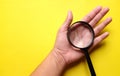 Woman hand holding Magnifying glass  on a yellow background Royalty Free Stock Photo