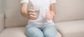 woman hand holding medicine painkiller pill and water glass on the sofa at home, taking for headaches, stomach ache, Diarrhea Royalty Free Stock Photo