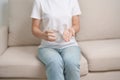 woman hand holding medicine painkiller pill and water glass on the sofa at home, taking for headaches, stomach ache, Diarrhea Royalty Free Stock Photo