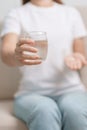 woman hand holding medicine painkiller pill and water glass on the sofa at home, taking for headaches, stomach ache, Diarrhea Royalty Free Stock Photo