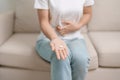 woman hand holding medicine painkiller pill and water glass on the sofa at home, taking for headaches, stomach ache, Diarrhea Royalty Free Stock Photo