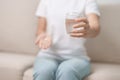 woman hand holding medicine painkiller pill and water glass on the sofa at home, taking for headaches, stomach ache, Diarrhea Royalty Free Stock Photo