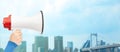 Woman hand holding megaphone over city background Royalty Free Stock Photo