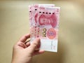 Woman hand holding one hundred Chinese yuan money on yellow background. Royalty Free Stock Photo