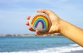 Woman hand holding pebble with painted rainbow Royalty Free Stock Photo