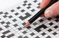 Woman hand holding a pencil and solves crossword