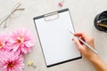 Woman hand holding pencil and writing a text into blank paper clipboard mockup. Flat lay home office desk. Top view female Royalty Free Stock Photo