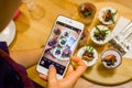 Woman hand holding phone taking photo of tasty Cupcakes with berries. Instagram photography blogging and sweets concept