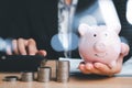 Woman hand holding piggy bank with money stack step up growing growth on wood table Royalty Free Stock Photo