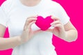 Woman hand holding plush a red heart at left her chest on pink background Royalty Free Stock Photo