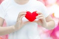 Woman hand holding plush a red heart at left her chest on pink background Royalty Free Stock Photo