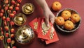 Woman hand holding pow or red packet, orange and gold ingots on a red background