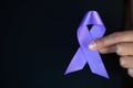 Woman Hand Holding Purple Ribbon, Domestic Violence Awareness Month October concept with deep purple awareness ribbon