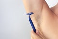 Woman hand holding razor to shave hairy unshaved armpit holding arm aside on the white background