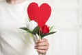 Woman hand holding red paper heart shape and flowers for valentine`s day.