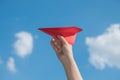 Woman hand holding a red paper rocket with a bright blue background Royalty Free Stock Photo