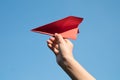 Woman hand holding a red paper rocket with a bright blue background Royalty Free Stock Photo