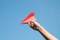 Woman hand holding a red paper rocket with a bright blue background Royalty Free Stock Photo