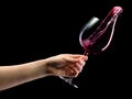 Woman hand holding red wine glass with splashes isolated on black Royalty Free Stock Photo