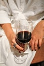 Woman hand holding red wine glass with stylish make-up in white dress. A full glass of wine in the graceful hand of a girl. Royalty Free Stock Photo