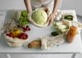 Woman hand holding Reusable eco textile grocery bag with vegetables and takes cabage out. Zero waste and plastic free